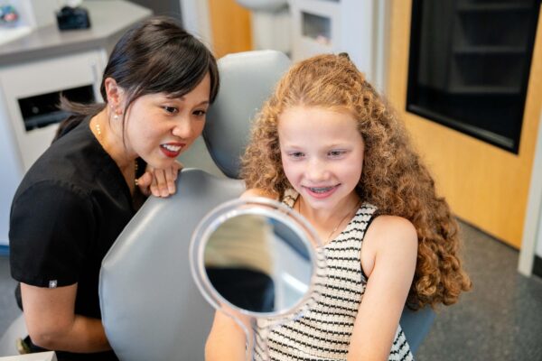 Young girl smiling at her reflection during a braces appointment at Dr. Matt Orthodontics in Beaverton