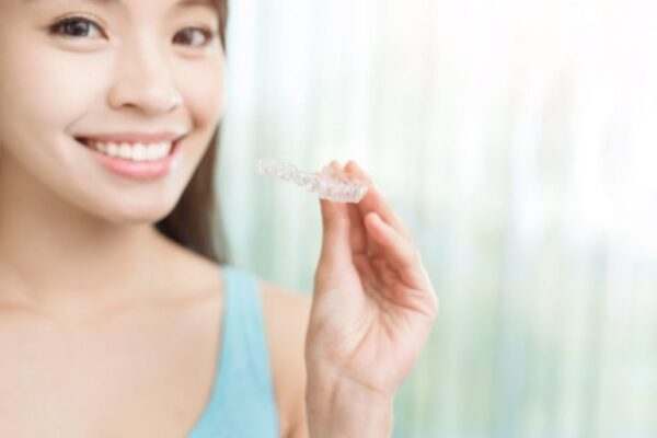 Patient holding custom clear aligners at Dr. Matt Orthodontics in Beaverton, Oregon