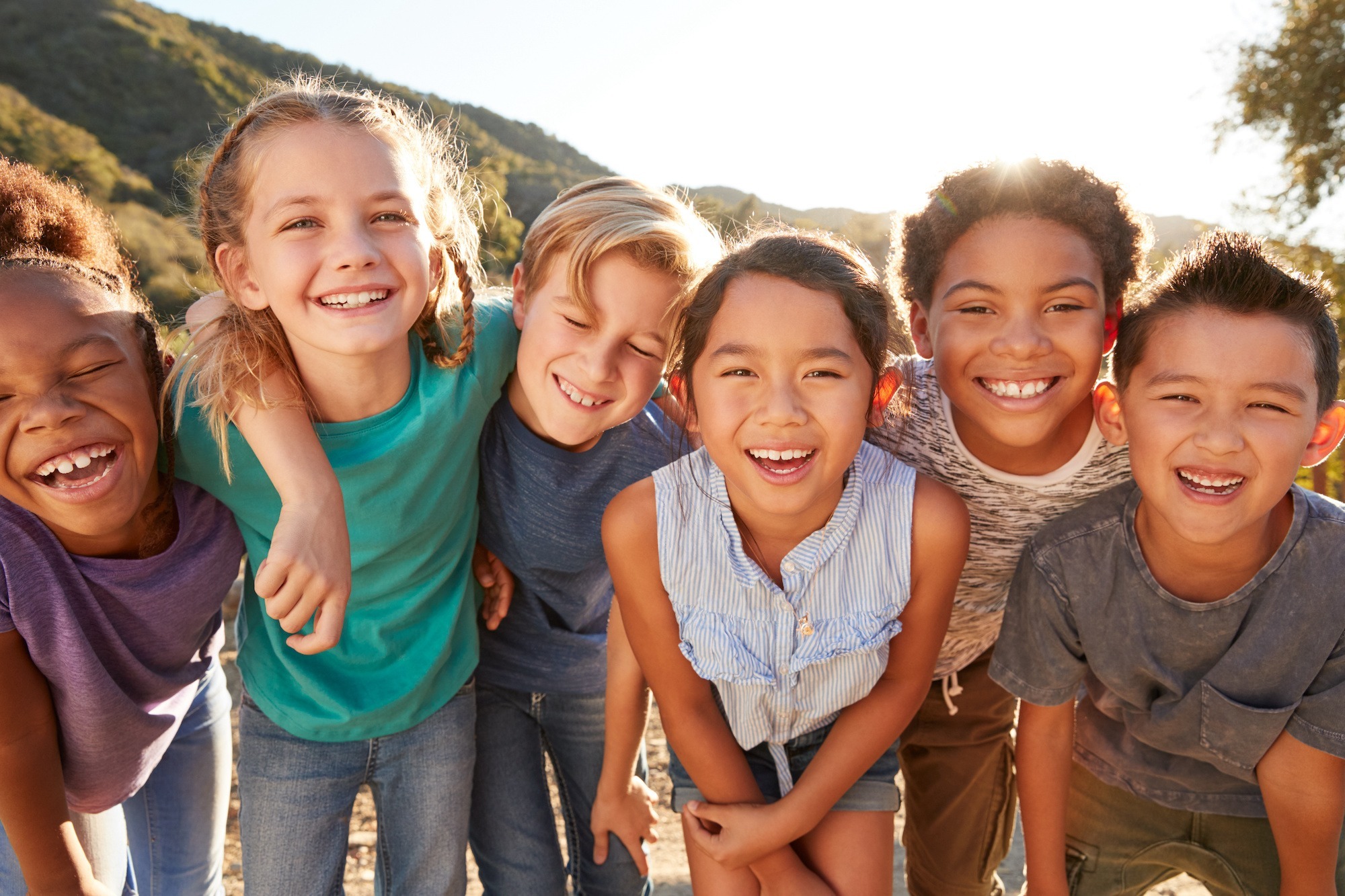 Group of happy children smiling outdoors, representing the positive outcomes of orthodontic treatment at Dr. Matt Orthodontics in Beaverton, emphasizing the joy of achieving a healthy smile with braces or clear aligners.